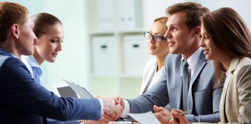 Image of confident businessmen handshaking at meeting